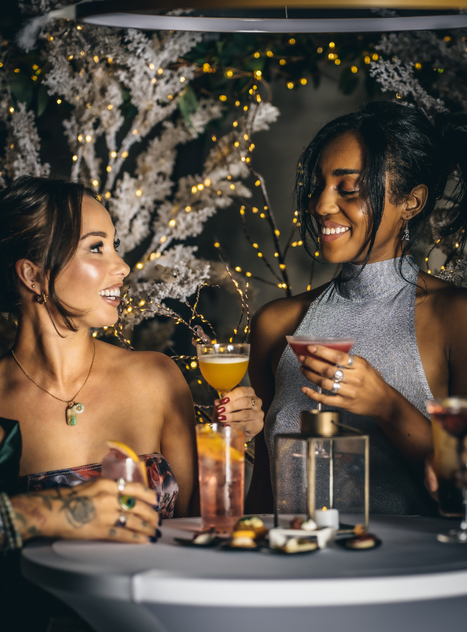 Two women enjoying cocktails at a winter celebration at Wagtail Rooftop Bar and Restaurant