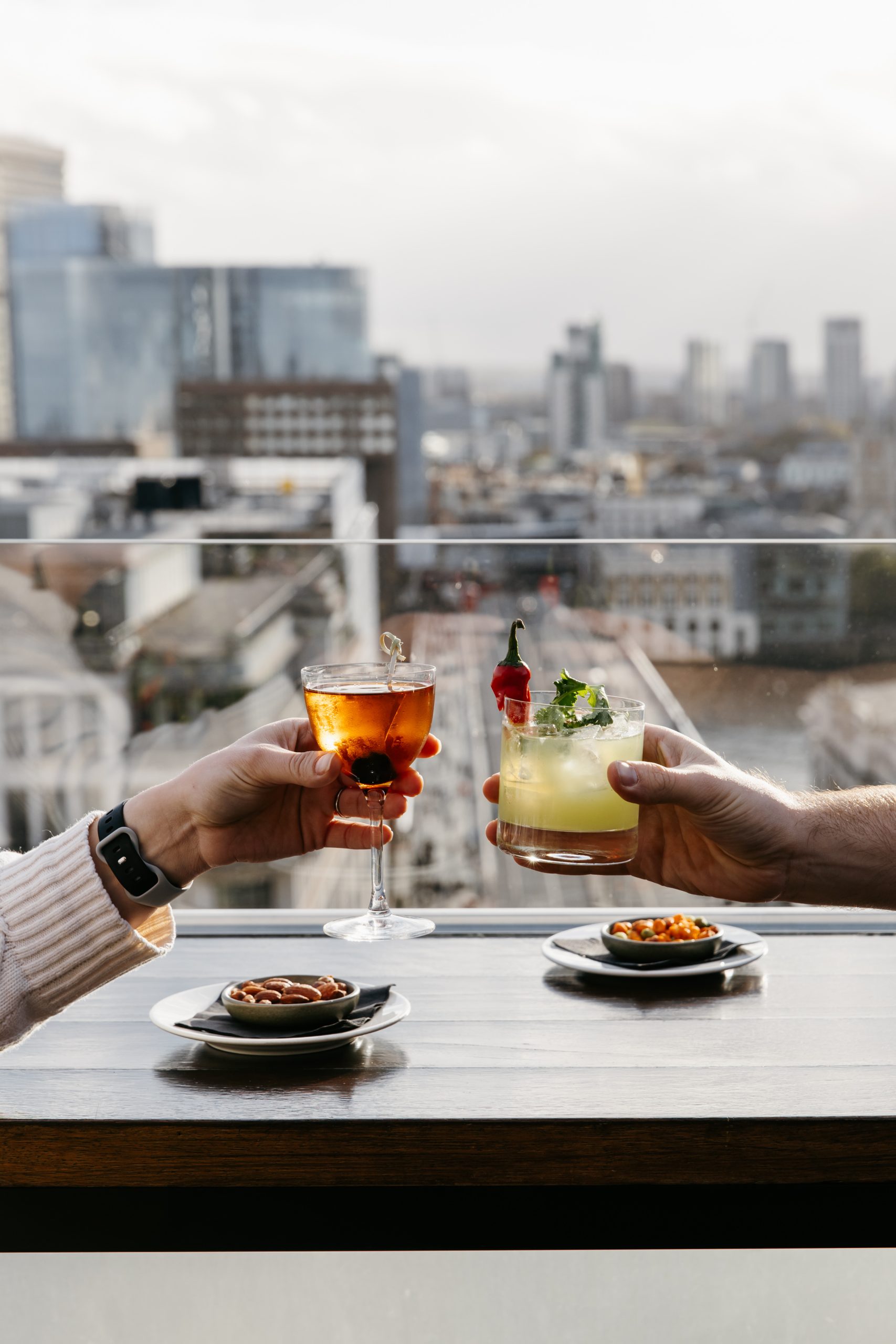 Two cocktails preparing to toast at a terrace bar